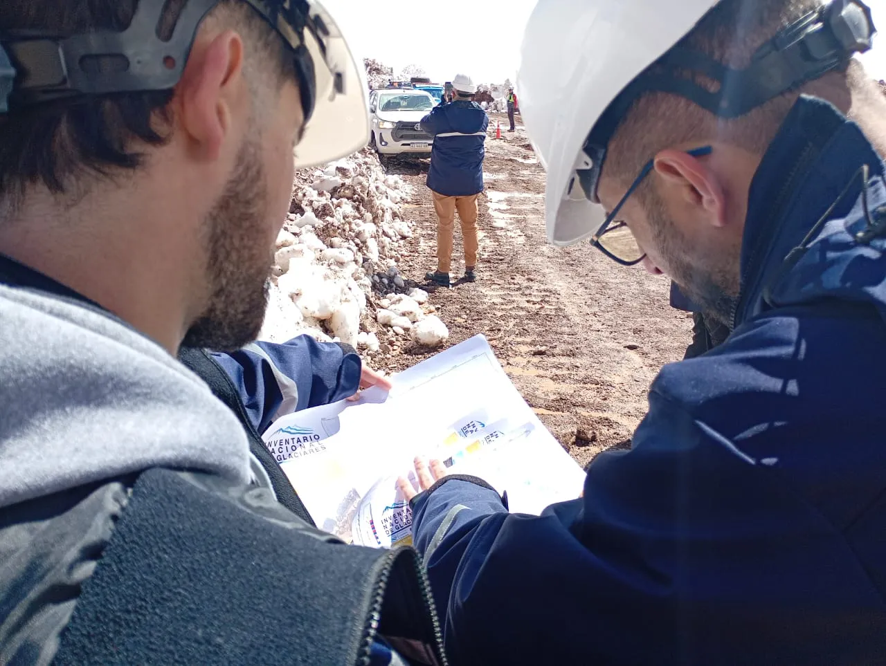 Contenido Original de ACERO Y ROCA - Prohibida su reproducción equipo de seguridad estudian un plano técnico detallado de la infraestructura del sitio minero sobre el capó de una camioneta en Los Azules.