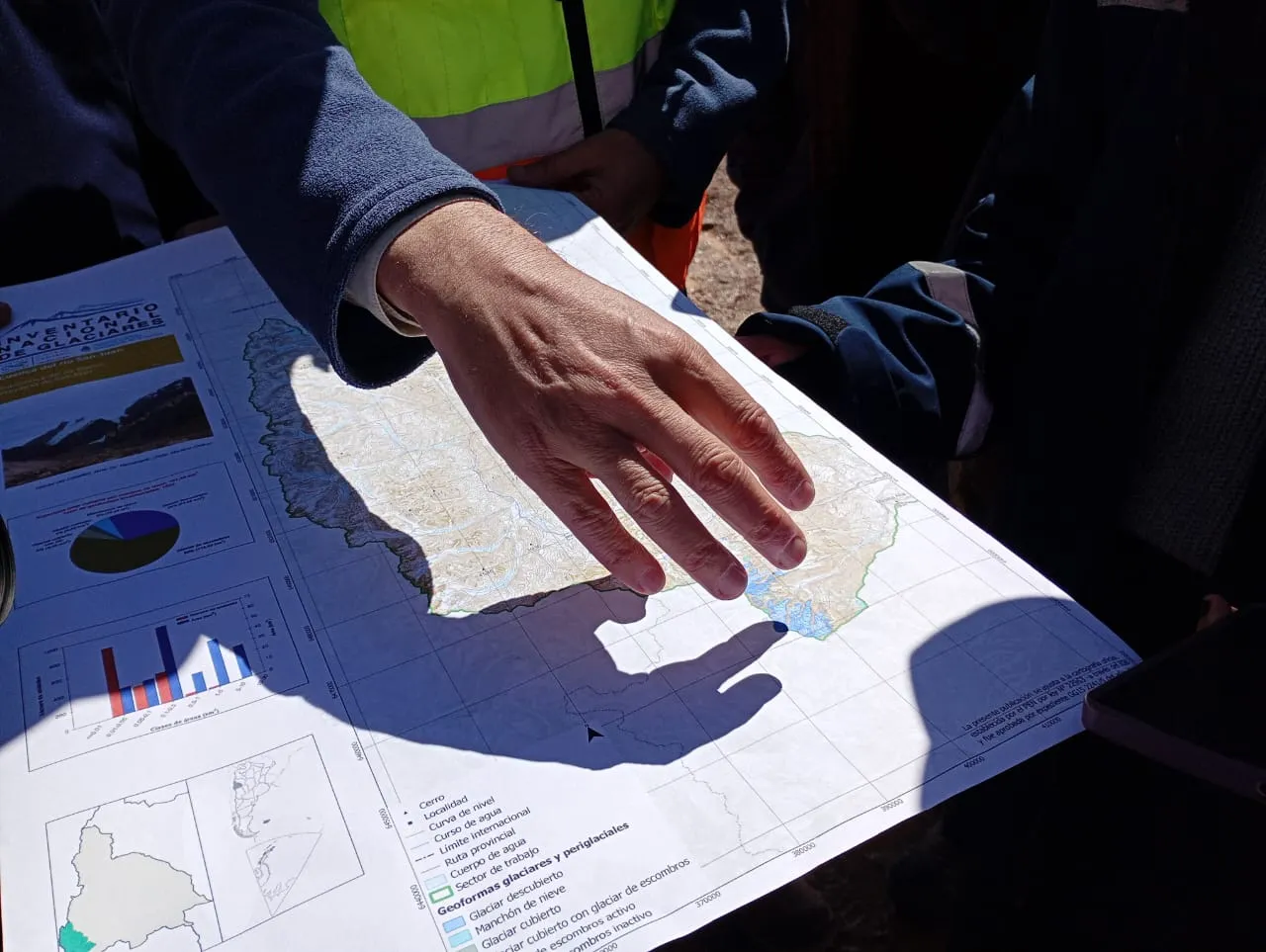 Contenido Original de ACERO Y ROCA - Prohibida su reproducción Detalle de mano señalando la traza y límites del camino a Los Azules en un mapa.
